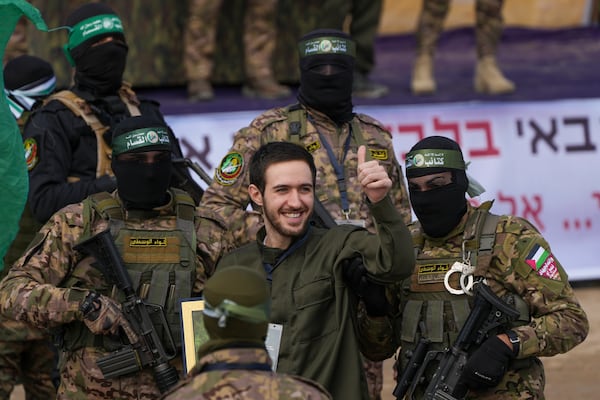 Israeli hostage Omer Shem, centre, is escorted by Hamas fighters before being handed over to the Red Cross in Nuseirat, central Gaza Strip, Saturday, Feb. 22, 2025. (AP Photo/Abdel Kareem Hana)