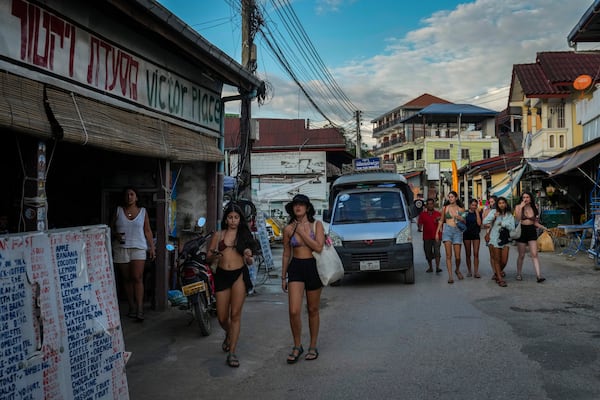 Foreign tourists walk in a street near bars in Vang Vieng, Laos, Tuesday, Nov. 19, 2024. (AP Photo/Anupam Nath)