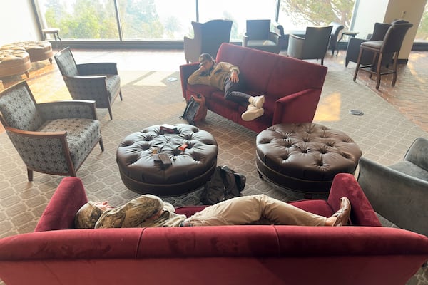 Students sleep on couches on the Pepperdine University campus, where a makeshift shelter was set up as the Franklin Fire closed in Tuesday, Dec. 10, 2024, in Malibu, Calif. (AP Photo/Damian Dovarganes)