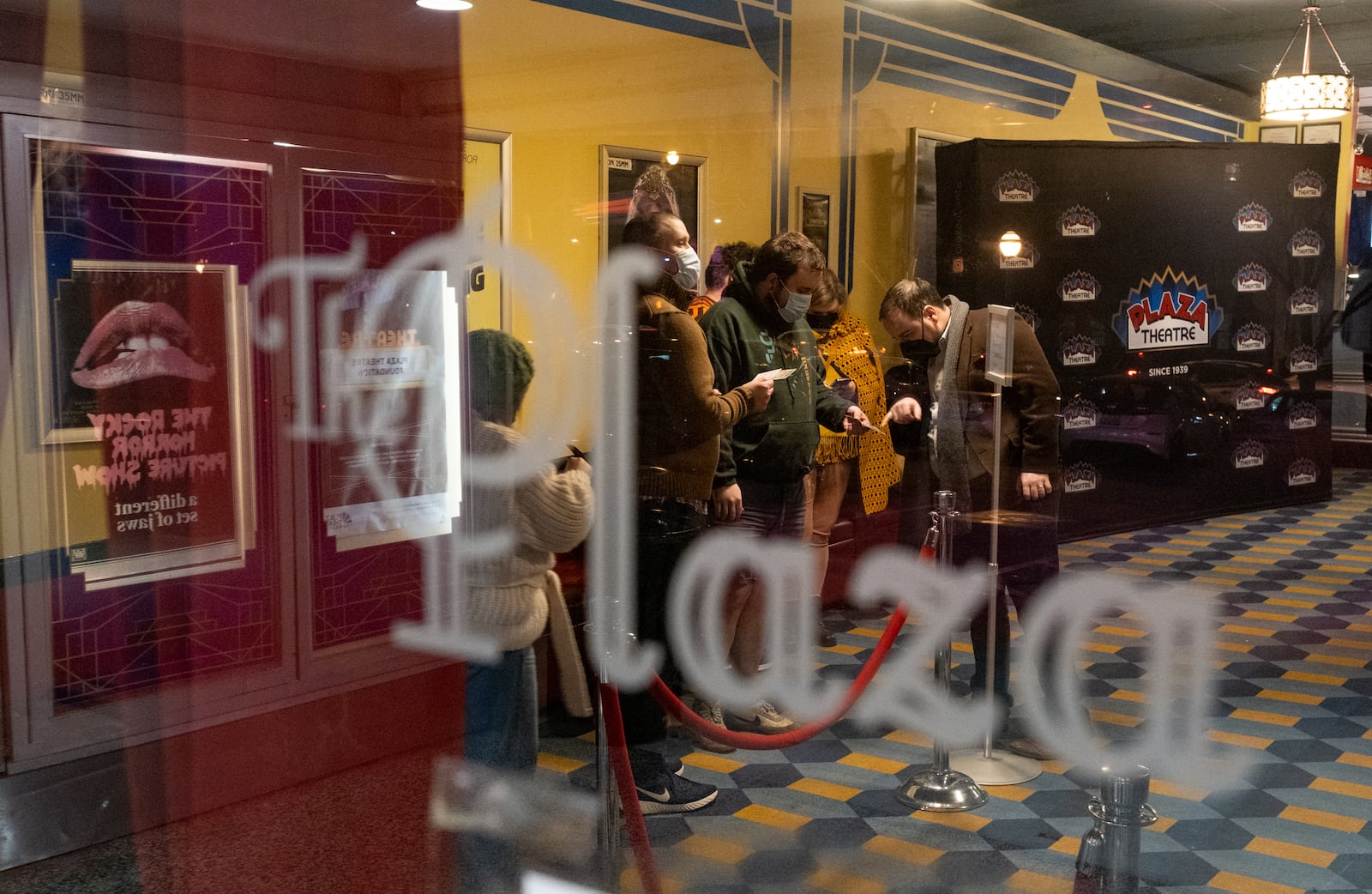 Christopher Escobar, owner of the Plaza Theatre, checks patrons’ vaccination cards one Saturday night in January, before a 35mm showing of “The Shining.”  Ben Gray for the Atlanta Journal-Constitution