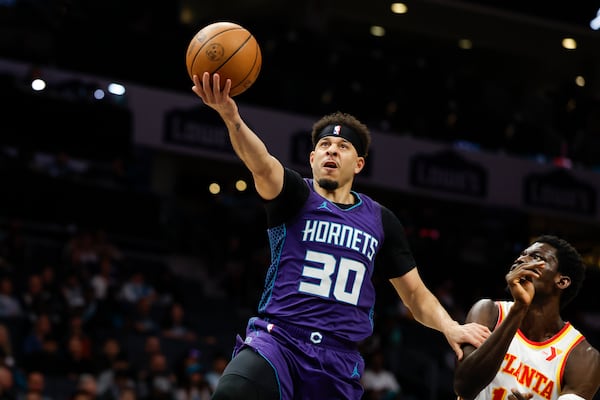 Charlotte Hornets guard Seth Curry (30) drives to the basket past Atlanta Hawks forward Mouhamed Gueye during the first half of an NBA basketball game in Charlotte, N.C., Tuesday, March 18, 2025. (AP Photo/Nell Redmond)