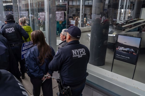 Demonstrators are arrested by NYPD officers during a protest against Elon Musk and Tesla outside of a Tesla showroom, Saturday, March 01, 2025 in New York. (AP Photo/Adam Gray)