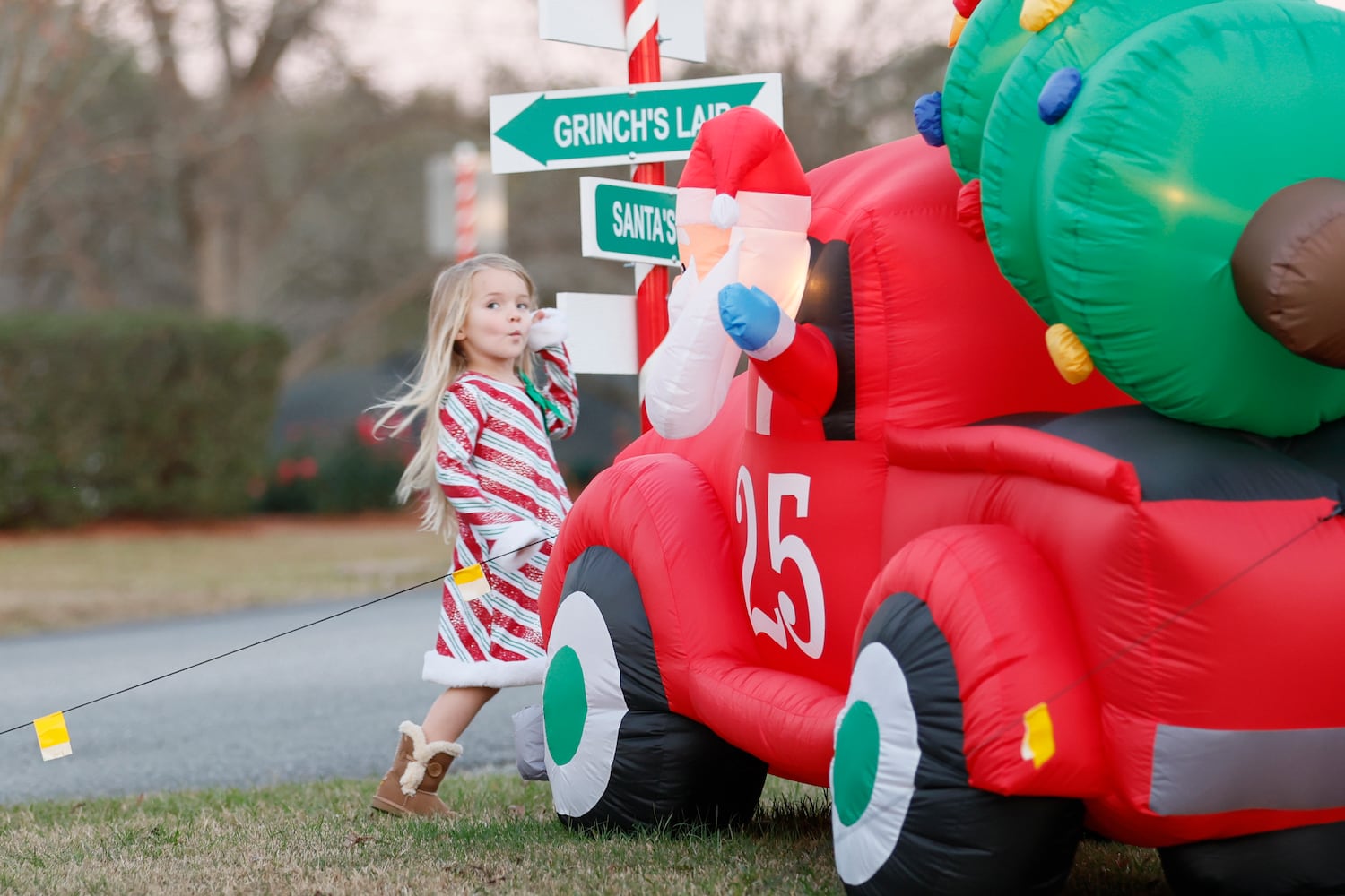 Alayna Jernigan walks around an inflatable Christmas decoration as her grandparents, Renee and Walter Wright, try to take a photo at one of the intersections decorated with candy cane stripes in the town of Santa Claus.
 Miguel Martinez / miguel.martinezjimenez@ajc.com