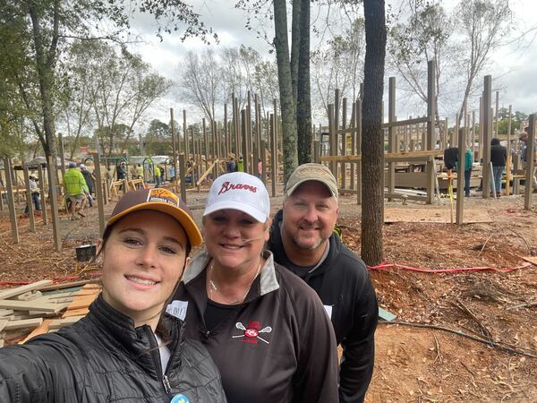 Addison Olvey (from left), Autumn Ernst and her current husband smile for a photo while volunteering at PlayTown Suwanee on Thursday.