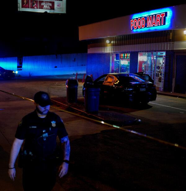 An Atlanta police officer stands at the scene of a shooting at a food mart on Metropolitan Parkway on Tuesday morning. 