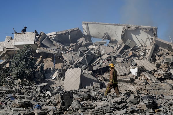 A civil defense worker and civilians check a building that collapsed after it was hit in an Israeli airstrike in Hadath, south of Beirut, Lebanon, Sunday, Nov. 17, 2024. (AP Photo/Bilal Hussein)