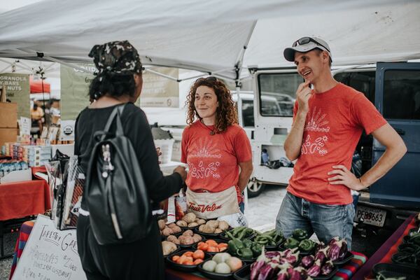 Flannery Pearson-Clarke (center) and Bobby Farmer of Food Well Alliance talk to an East Point Farmers Market customer about produce from Tapestry Community Garden. CONTRIBUTED BY CALEB JONES