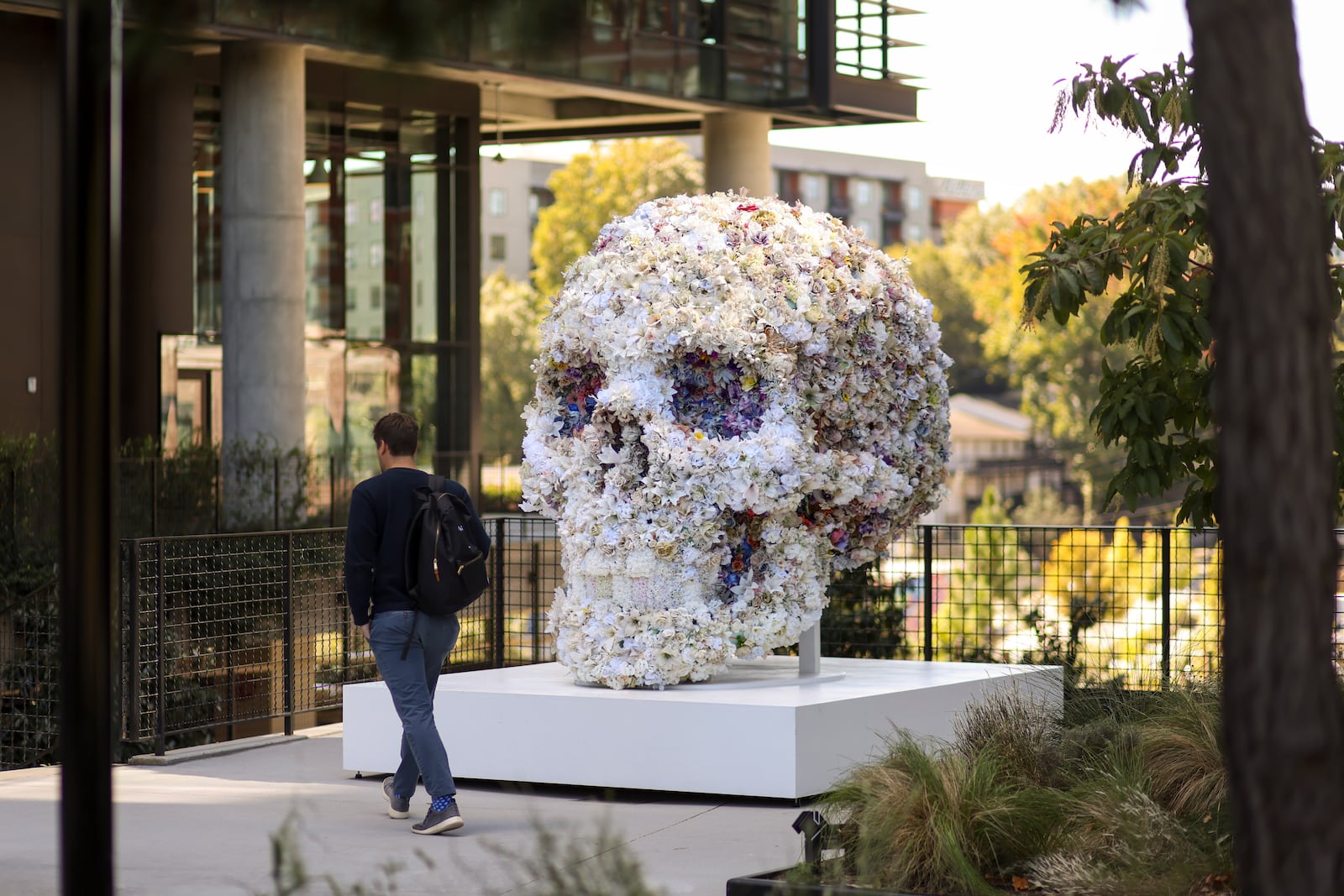 A man walks by an art installation of a giant skull made of flowers along the Beltline's Eastside Trail.
