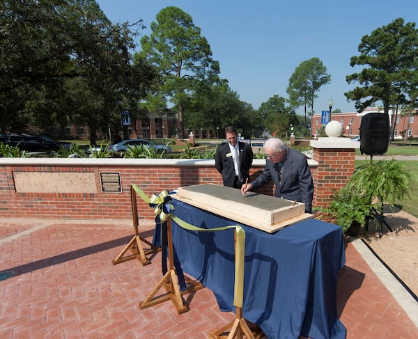 Georgia Southwestern State University President Neal Weaver, left, looks on as former President Jimmy Carter signs his name in wet concrete at the 2017 Presidential Plaza dedication. PHOTO CONTRIBUTED