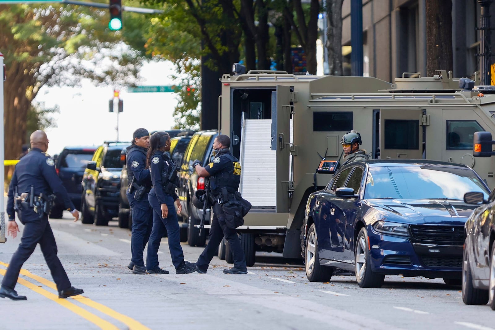 Members of the Atlanta Police Department and SWAT team stood on 14th Street outside the Four Seasons Hotel in Midtown Atlanta, where a suspect fired shots inside the hotel on Tuesday, Oct. 29, 2024. (Miguel Martinez/Atlanta Journal-Constitution via AP)