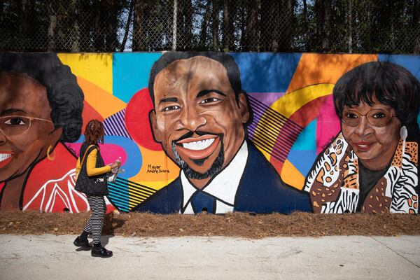 A passerby looks at the new mural in Adamsville featuring Atlanta Mayor Andre Dickens and other community leaders. The new art piece was unveiled on Oct. 5, 2023 along M.L.K. Jr. Drive in Atlanta. (Riley Bunch/riley.bunch@ajc.com)