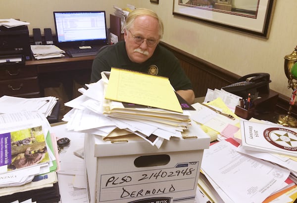 In 2015, a year after the deadly crimes, Putnam County Sheriff Howard Sills inspects the already collected documents related to the murders of Russell and Shirley Dermond.  (Photo: Christian Boone/AJC)