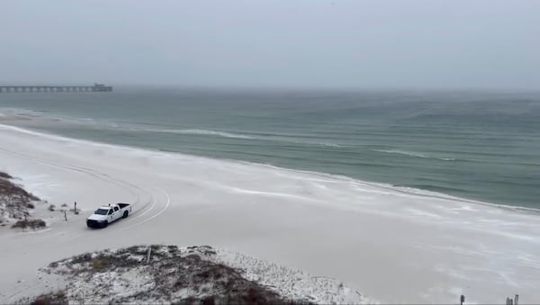 This photo provided by Kylee Thompson shows a truck driving on a snowy beach in Gulf Shores, Ala., on Tuesday, Jan. 21, 2025. (Kylee Thompson via AP)