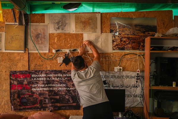 An activist fixes maps of the Armenian quarter on the wall inside a makeshift camp sets up in a parking lot at the Armenian quarter in Jerusalem, Thursday, Nov. 21, 2024. (AP Photo/Francisco Seco)