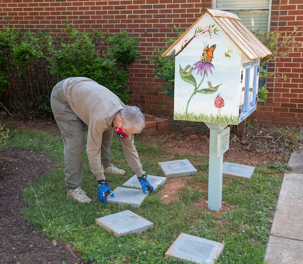 Co-chair Carolyn Chandler places stepping stones around a lending library in the new garden area in front of Avondale Elementary School which also features hand-painted totem poles. The Avondale Estates Garden Club and the Avon Garden Club worked together on the project.
PHIL SKINNER FOR THE ATLANTA JOURNAL-CONSTITUTION.