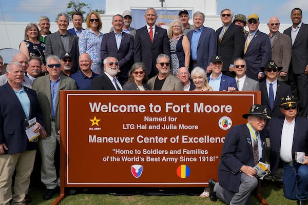 People pose for photos next to a newly unveiled Fort Moore sign during a ceremony to redesignate Fort Benning as Fort Moore, at Doughboy Stadium in Columbus, Georgia, on May 11, 2023.  (Photo by CHENEY ORR / AFP) (Photo by CHENEY ORR/AFP via Getty Images)