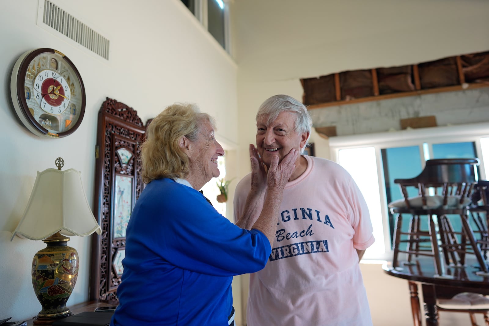 Ron and Jean Dyer, high school sweethearts who have been married for 60 years, joke together as they talk in the living room of their second-floor beachfront condominium, which lost its roof and a section of wall during Hurricane Milton, in Venice, Fla., Saturday, Oct. 12, 2024. (AP Photo/Rebecca Blackwell)