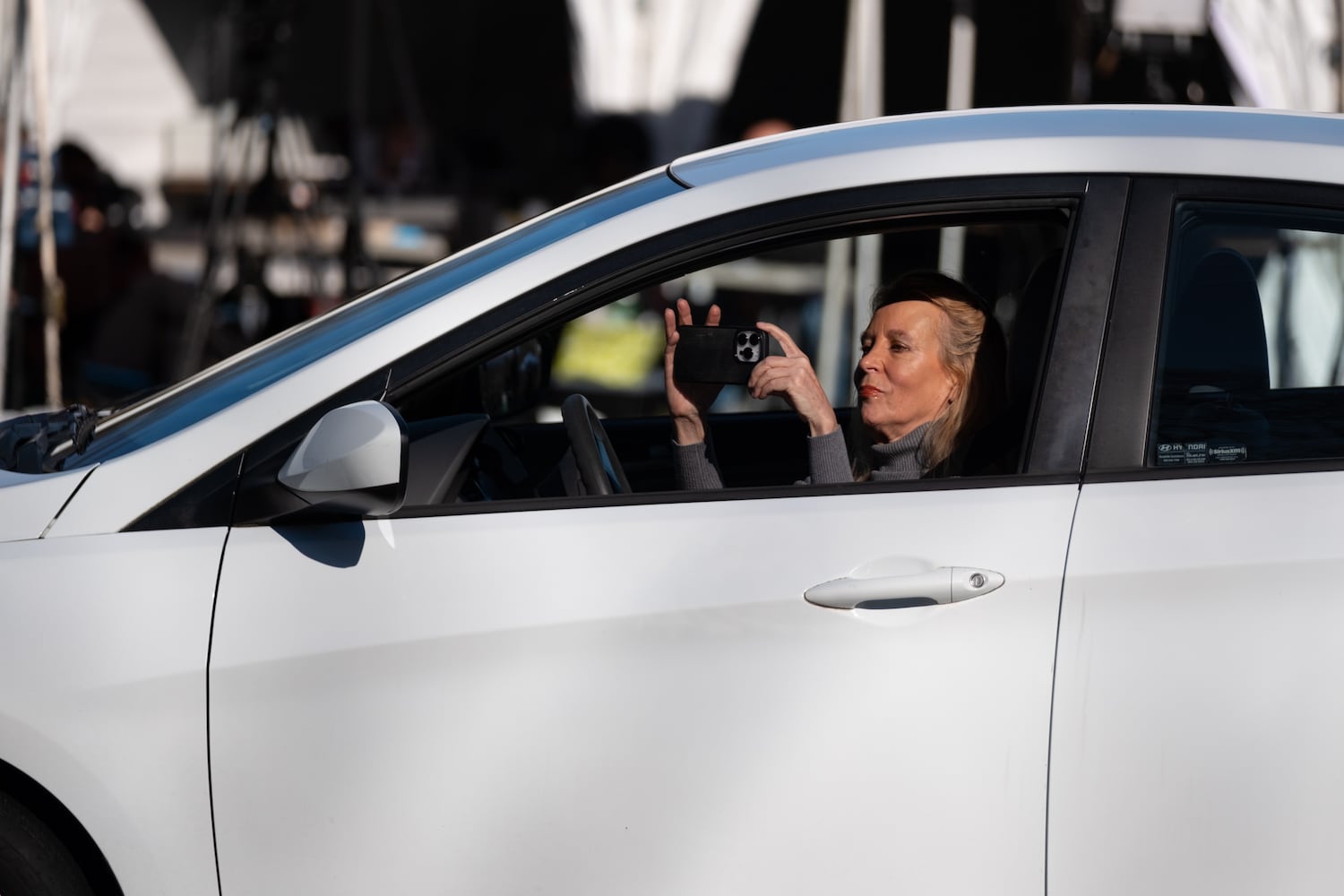 A woman drives by and photographs a makeshift memorial to former President Jimmy Carter at the Carter Center in Atlanta on Monday, Dec. 30, 2024.   Ben Gray for the Atlanta Journal-Constitution