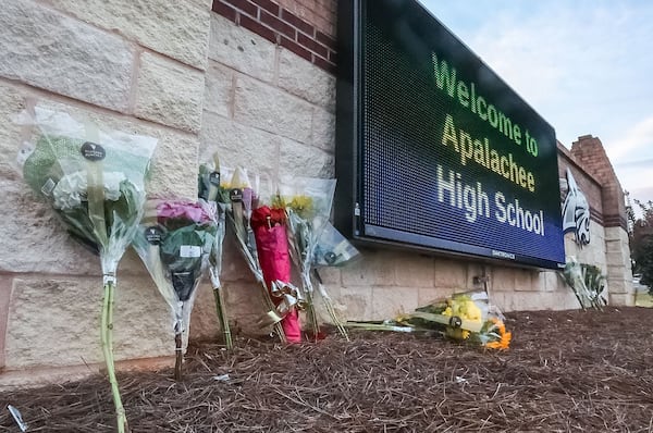 Flowers are placed at the foot of the welcome sign to Apalachee High School for a makeshift memorial on Sept. 5, 2024. (John Spink/The Atlanta Journal-Constitution/TNS)