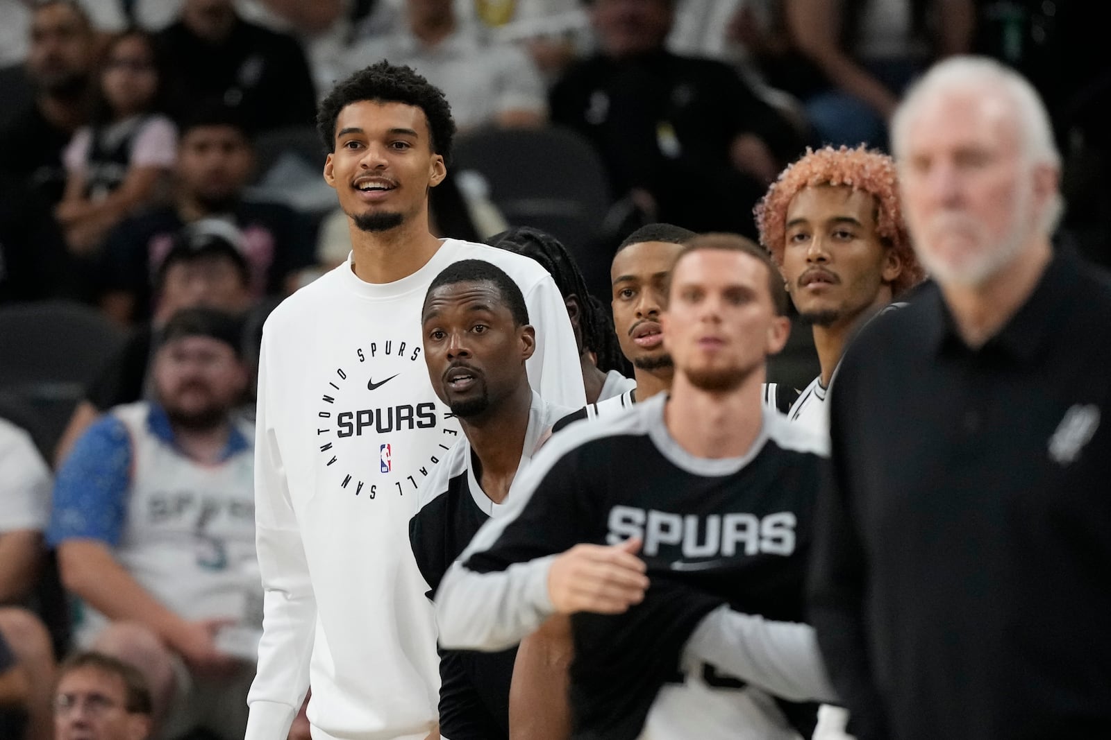 San Antonio Spurs center Victor Wembanyama, left, watches from the bench during the second half of a preseason NBA basketball game against the Oklahoma City Thunder in San Antonio, Monday, Oct. 7, 2024. (AP Photo/Eric Gay)