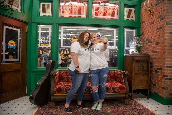 Best friends Tara Grier (left) and Kayte McAlexander pose for a photo in the set recreation of the Central Perk Cafe at "The Friends Experience" in Sandy Springs. Alyssa Pointer/Atlanta Journal Constitution