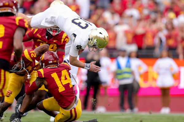 Notre Dame quarterback Riley Leonard, top, dives over Southern California cornerback Greedy Vance Jr., left, and cornerback Jacobe Covington during the first half of an NCAA football game, Saturday, Nov. 30, 2024, in Los Angeles. (AP Photo/Ryan Sun)