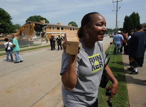 Glenda McKennie, former librarian at the Bowen Homes, carries a brick from the demolition of the Bowen Homes on June 3, 2009. (AJC file)