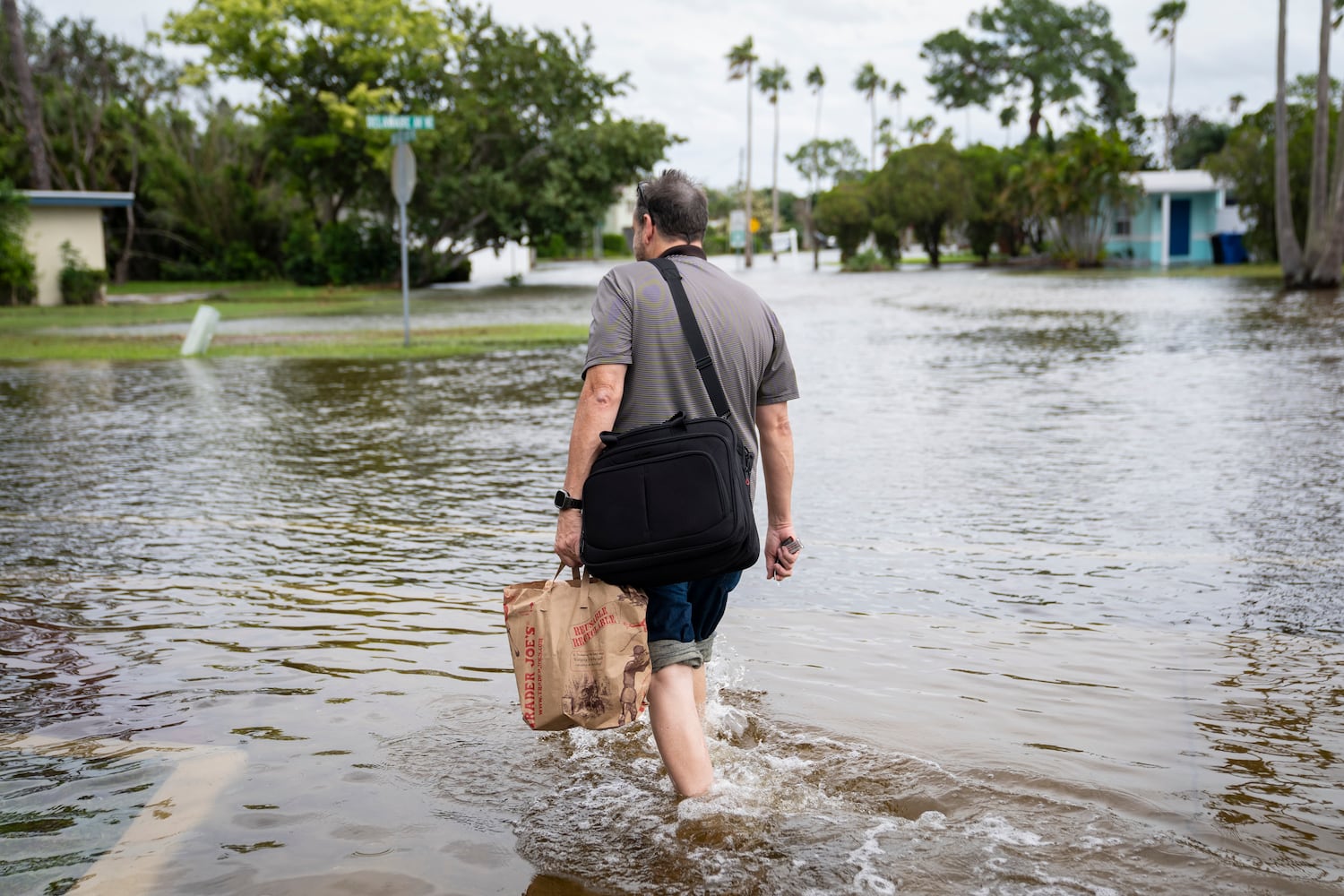 A man walks through the rising floodwaters in the Shore Acres neighborhood of St. Petersburg, Fla., on Sept. 26, 2024. (Nicole Craine/The New York Times)