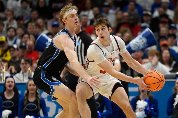 Wisconsin guard Jack Janicki, right, looks to pass the ball as Brigham Young forward Richie Saunders defends during the first half in the second round of the NCAA college basketball tournament Saturday, March 22, 2025, in Denver. (AP Photo/John Leyba)