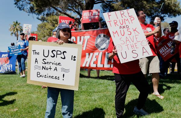 Protesters hold signs during a "Fight Like Hell" rally, part of a national series of rallies held to protest the Trump administration's plans to privatize or restructure the U.S. Postal Service, Sunday, March 23, 2025, in Las Vegas. (Steve Marcus/Las Vegas Sun via AP)