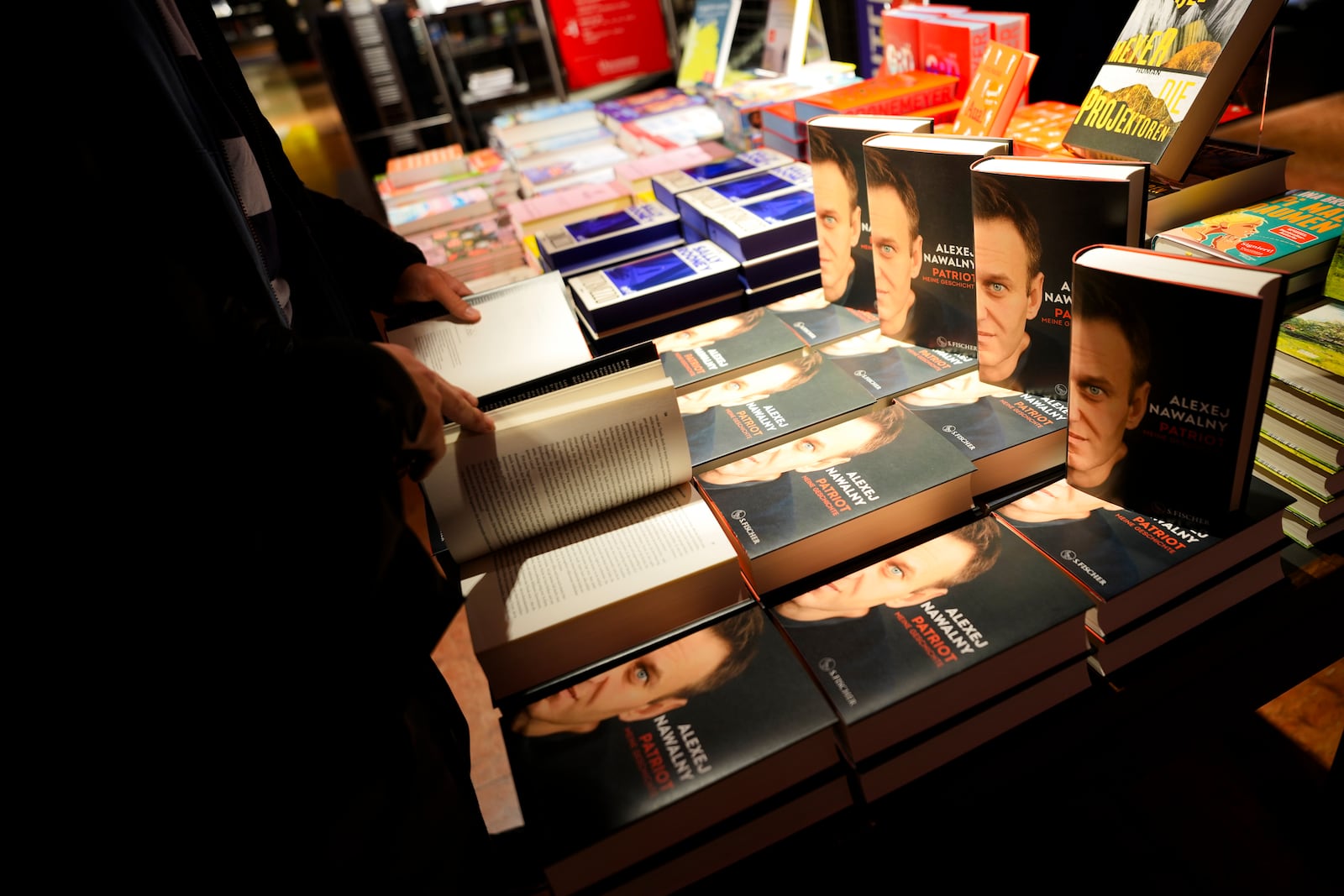 Customers look at copies of the late Russian opposition leader Alexei Navalny's memoir entitled 'Patriot' are put display on the first day of sale in a bookshop in Berlin, Germany, Tuesday, Oct. 22, 2024. (AP Photo/Markus Schreiber)