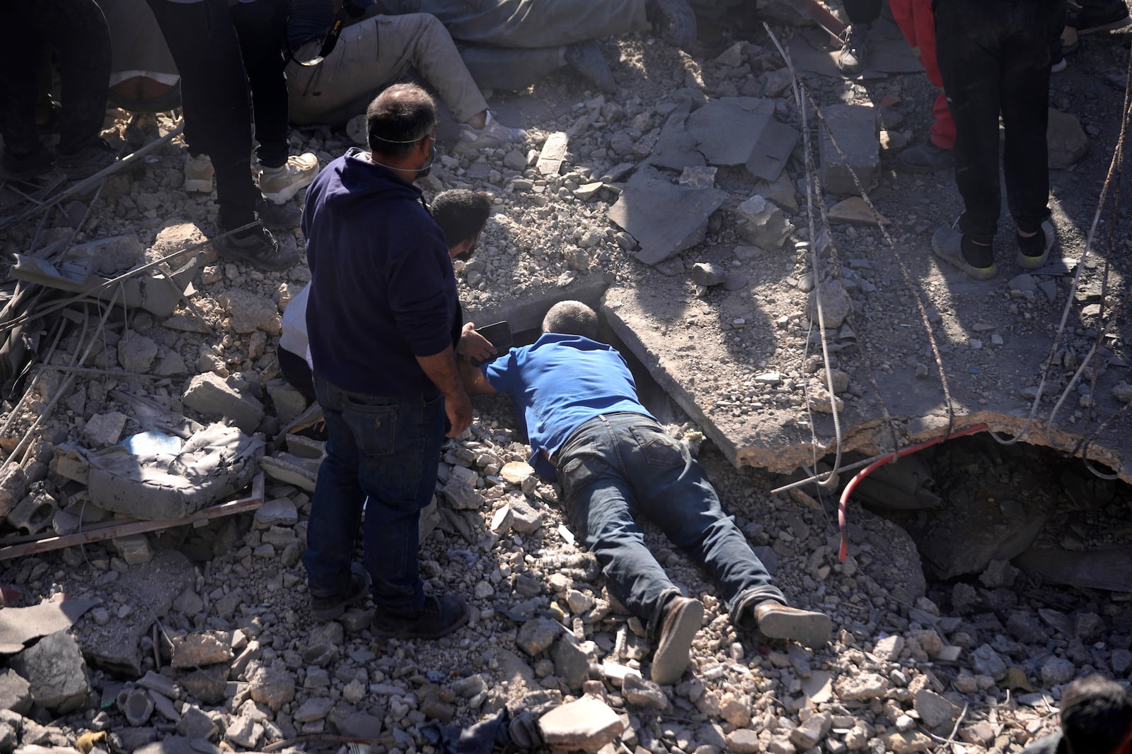 A man searches for a missing relative under the rubble of a destroyed building at the site of Israeli airstrikes, facing the city's main government hospital in a densely-populated neighborhood, in southern Beirut, Lebanon, Tuesday, Oct. 22, 2024. (AP Photo/Hussein Malla)