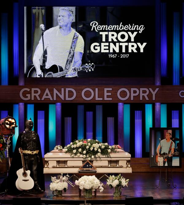 A Batman costume and guitar appear next to the casket during a memorial service for country music singer Troy Gentry at the Grand Ole Opry House Thursday, Sept. 14, 2017, in Nashville, Tenn. Gentry, who was a fan of Batman and made up the duo Montgomery Gentry with Eddie Montgomery, died Sept. 8 in a helicopter crash. (AP Photo/Mark Humphrey)