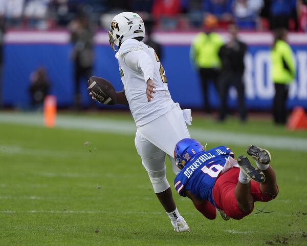 Kansas linebacker Taiwan Berryhill Jr. (6) tries to tackle Colorado quarterback Shedeur Sanders (2) during the first half of an NCAA college football game, Saturday, Nov. 23, 2024, in Kansas City, Mo. (AP Photo/Charlie Riedel)