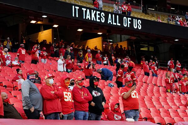 Fans stand for a presentation on social justice before season opening between the Kansas City Chiefs and the Houston Texans Thursday, Sept. 10, 2020, in Kansas City, Mo. Fans were allowed inside Arrowhead, and while masks were required, Native American headdresses and face painting were not allowed. (AP Photo/Charlie Riedel)