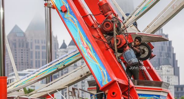 Daniel Armenta with Reithoffer Shows prepares the Ferris wheel at the Dogwood Festival at Piedmont Park on Friday morning.