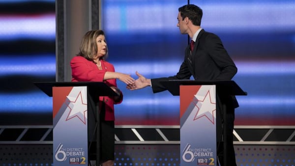 Republican Karen Handel and Democrat Jon Ossoff shake hands before a debate in 2017, when they were running for a suburban Atlanta U.S. House seat. Back then, Ossoff worked  hard to distance himself from national Democrats such as Nancy Pelosi. This year, Ossoff is taking a different tack.