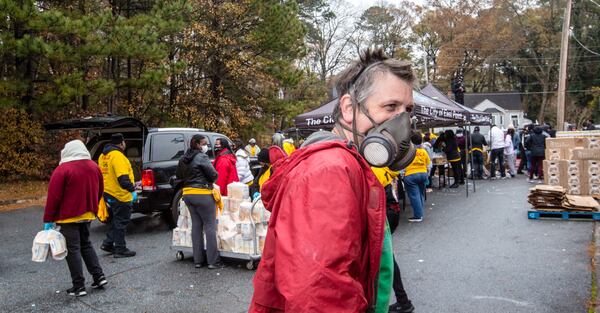 Thomas Calloway, an East Point city council member, and volunteers work to distribute dry goods, fresh fruits and vegetables and frozen meats to cars waiting in long lines at Jefferson Park Recreation Center in East Point. (Jenni Girtman for The Atlanta Journal-Constitution)