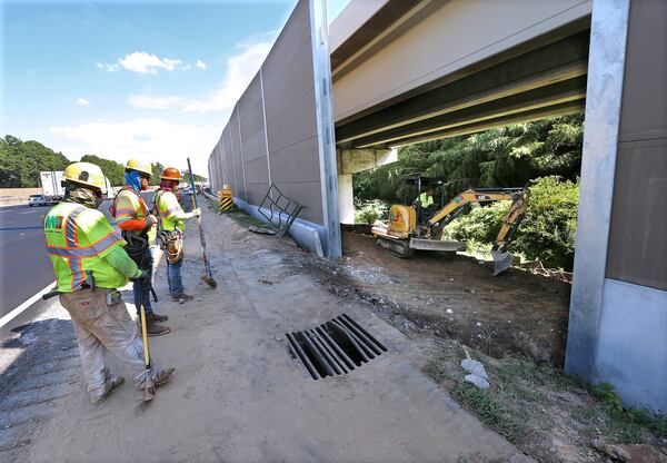 Construction workers look over a section of the Northwest Corridor Express Lanes project on Interstate 75 South close to Windy Hill Road, near where a wall collapsed recently in Cobb County. Curtis Compton/ccompton@ajc.com