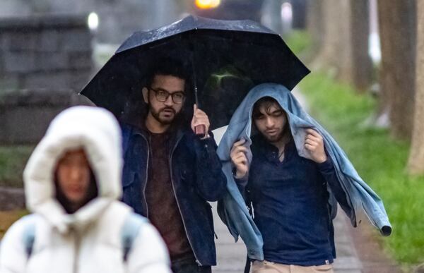 Pranav Shaime (left) holds an umbrella for Vaibhav Malhotra, a fellow robotics masters student, as they traverse Georgia Tech's campus in the rain. 
