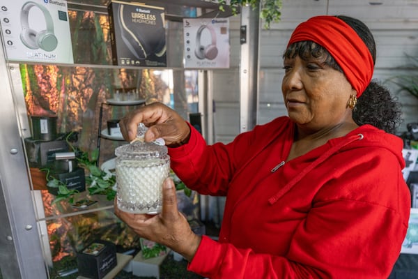 Felicia Flecha-Johnson talks about her line of homemade candles while posing for a photograph at her booth at Sweeties Flea Market, located off U.S. 19/41 in Hampton.  Steve Schaefer/steve.schaefer@ajc.com