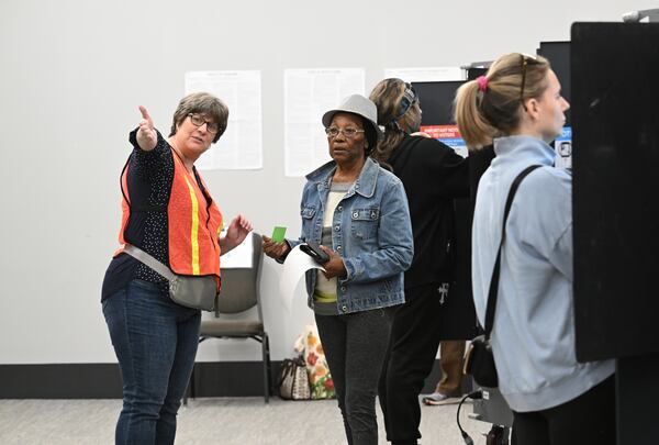 Joyce Fraser (center) of Marietta, is directed a poll worker after filling her ballot at the polling station during the advance voting at Cobb County Elections and Registration Main Office, Tuesday, October 15, 2024, in Marietta. (Hyosub Shin / AJC)