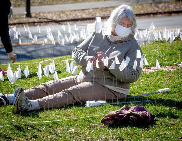 Kathy Morse helps plant flags to represent the number of COVID-19 deaths in Georgia. The display served as a "public mourning space" said organizer Tim Franzen. (Photo: Steve Schaefer for The Atlanta Journal-Constitution)