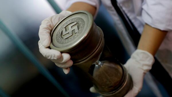 A member of the federal police holds an hourglass with Nazi markings at the Interpol headquarters in Buenos Aires, Argentina, Friday, June 16, 2017. In a hidden room in a house near Argentina's capital, police discovered on June 8th the biggest collection of Nazi artifacts in the country's history. Authorities say they suspect they are originals that belonged to high-ranking Nazis in Germany during World War II. (AP Photo/Natacha Pisarenko)