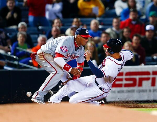 Atlanta Braves' Andrelton Simmons (19) is safe at third base as the ball gets away from Washington Nationals third baseman Yunel Escobar (5) in the fifth inning of a baseball game Monday, April 27, 2015, in Atlanta. Simmons was advancing to third from first base after a wild throw. Escobar was injured on the play and left the game.(AP Photo/John Bazemore) The ball is already out of Yunel Escobar's glove, and Andrelton Simmons still isn't on the ground. (John Bazemore/AP photo)