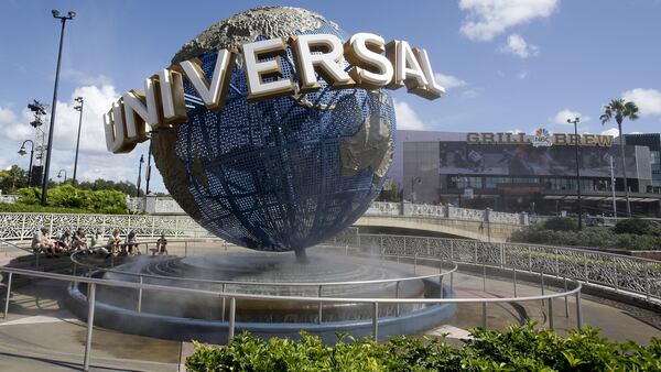 FILE-In this Thursday, Oct. 22, 2015 file photo, park guests relax and cool off with a water mist under the globe at Universal Studios City Walk in Orlando, Fla. ourism officials announced Monday, May 2, 2016, that the number of visitors coming to Orlando last year jumped 5.5 percent to more than 66 million visitors. That figure sets a record for tourists in Orlando and helps the central Florida city hang onto its bragging rights as the top tourist destination in the United States for the second year in a row. (AP Photo/John Raoux)