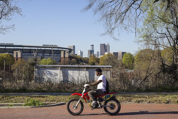 A man rides a dirt bike along brick-lined Atlanta Avenue in the Peoplestown community. 