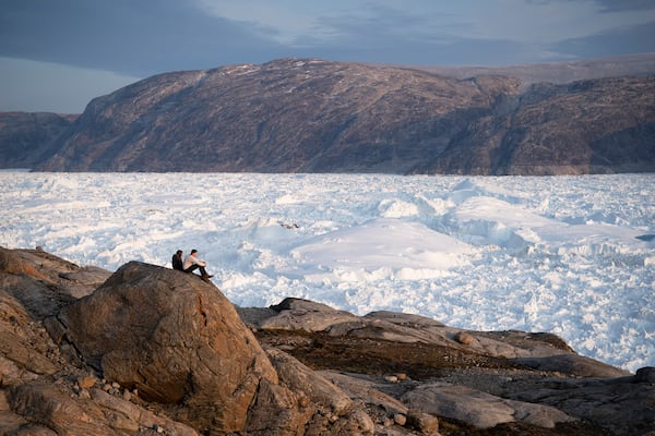 FILE - New York University student researchers sit on a rock overlooking the Helheim glacier in Greenland, Aug. 16, 2019. (AP Photo/Felipe Dana, File)