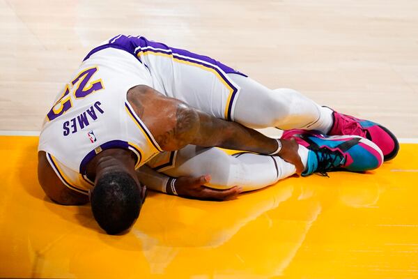 Los Angeles Lakers forward LeBron James holds his ankle after going down with an injury during the first half of an NBA basketball game against the Atlanta Hawks Saturday, March 20, 2021, in Los Angeles. (AP Photo/Marcio Jose Sanchez)