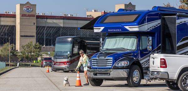 Paula Williams takes her dog, Tator, for a stroll as a few RVs already were parked at the Atlanta Motor Speedway on Tuesday morning, Oct. 8, 2024, with evacuees fleeing Hurricane Milton. Paula and her husband, Robert Williams, had just arrived after leaving their home in Clermont, Florida, near Orlando. Several Georgia hotels and campgrounds are opening their doors to evacuees. (John Spink/AJC)